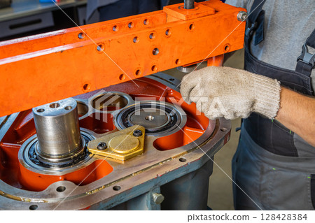 Mechanic assembling industrial gearbox in factory setting 128428384