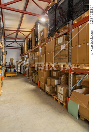 Cardboard boxes sitting on wooden pallets filling warehouse storage space Cardboard boxes sitting on wooden pallets filling warehouse storage space 128428394