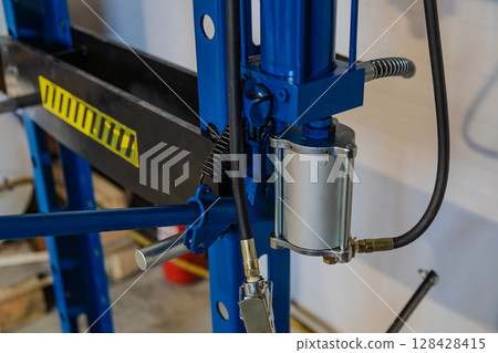 Hydraulic press showing cylinder, hoses, and handle in workshop Hydraulic press showing cylinder, hoses, and handle in workshop 128428415