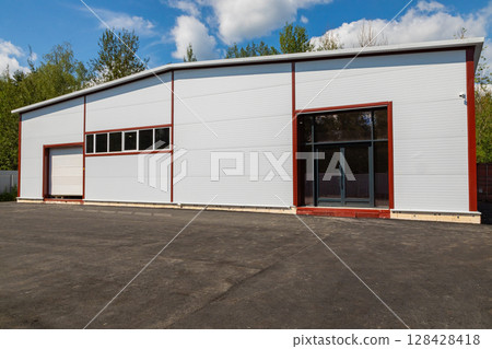 Modern warehouse building exterior with parking lot on a sunny day 128428418