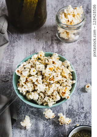 Delicious popcorn with dill and pickles in a bowl on the table vertical view 128428586
