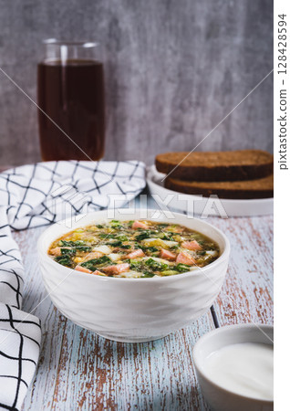 Traditional cold vegetable soup with kvass in a bowl on the table vertical view Traditional cold vegetable soup with kvass in a bowl on the table vertical view 128428594