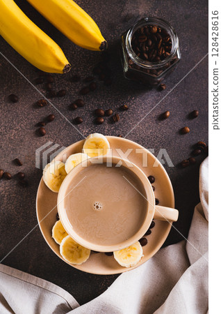 Blended frozen banana coffee in a cup on the table top and vertical view Blended frozen banana coffee in a cup on the table top and vertical view 128428616