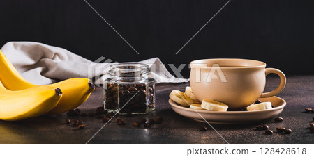 Blended frozen banana coffee in a cup on the table web banner 128428618