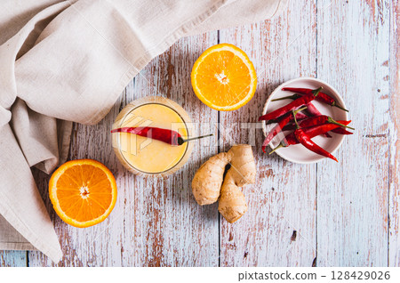 Smoothie with orange, ginger and cayenne pepper in a glass on the table top view Smoothie with orange, ginger and cayenne pepper in a glass on the table top view 128429026