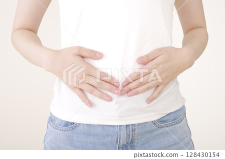 Woman placing hands on lower abdomen Woman placing hands on lower abdomen 128430154