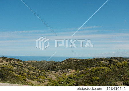 Scenic coastal road with view of Cabo da Roca lighthouse in Sintra Portugal curving highway through natural cliffs overlooking Atlantic Ocean under clear blue sky Scenic coastal road with view of Cabo da Roca lighthouse in Sintra Portugal curving highway through natural cliffs overlooking Atlantic Ocean under clear blue sky 128430241