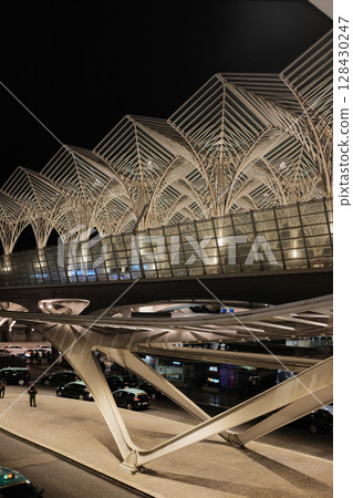 Modern illuminated architecture of Oriente Station at night in Lisbon Portugal featuring geometric roof design arches and empty railway tracks in futuristic urban environment. High quality photo Modern illuminated architecture of Oriente Station at night in Lisbon Portugal featuring geometric roof design arches and empty railway tracks in futuristic urban environment. High quality photo 128430247