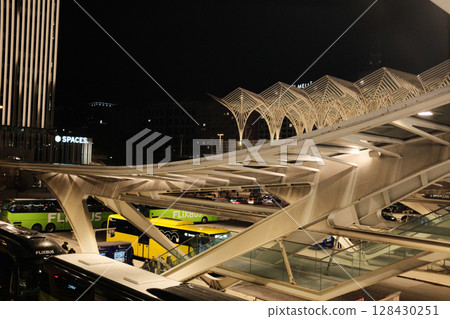 Modern illuminated architecture of Oriente Station at night in Lisbon Portugal featuring geometric roof design arches and empty railway tracks in futuristic urban environment. High quality photo Modern illuminated architecture of Oriente Station at night in Lisbon Portugal featuring geometric roof design arches and empty railway tracks in futuristic urban environment. High quality photo 128430251
