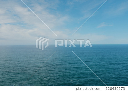 Scenic view of Cabo da Roca steep rocky cliffs meeting blue Atlantic Ocean under bright sky in Sintra Portugal panoramic coastal landscape from westernmost point of mainland Europe 128430273
