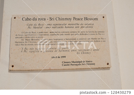 Commemorative stone plaque at Cabo da Roca westernmost point of continental Europe in Sintra Portugal historical marker with text tribute by Sri Chinmoy peace blossom. High quality photo 128430279