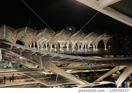 Modern illuminated architecture of Oriente Station at night in Lisbon Portugal featuring geometric roof design arches and empty railway tracks in futuristic urban environment. High quality photo Modern illuminated architecture of Oriente Station at night in Lisbon Portugal featuring geometric roof design arches and empty railway tracks in futuristic urban environment. High quality photo 128430337