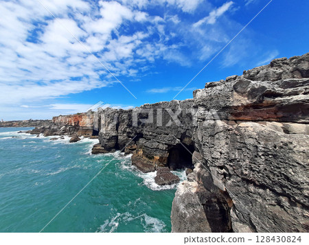 Dramatic cliffs and ocean waves at Boca do Inferno in Cascais Portugal under vibrant blue sky 128430824