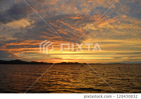 Golden sunset over the Adriatic Sea with distant Dinaric Alps silhouettes in Zadar, Croatia 128430832