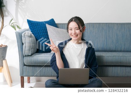 A woman using a computer in the living room A woman using a computer in the living room 128432216