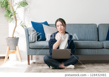 A woman using a computer in the living room A woman using a computer in the living room 128432481