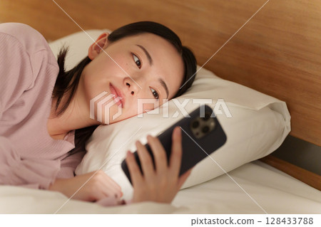 Woman using smartphone in bed at night Woman using smartphone in bed at night 128433788