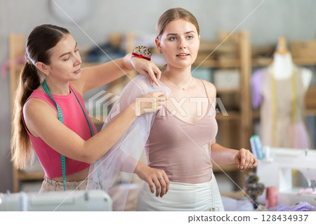dressmaker is trying on a sample of clothes with a client 128434937