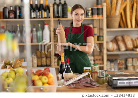 Young woman seller with wine in grocery store 128434938