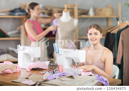 Adult woman sews female assistant working with mannequin 128434973