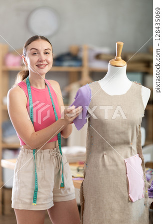 Woman seamstress adjusts clothes on mannequin 128435069