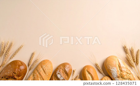 Bread and wheat lined up on beige background | Natural bakery frame viewed from above 128435071