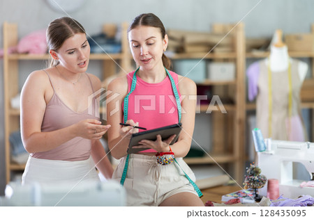 Two fashion designers drawing a sketch on a tablet 128435095
