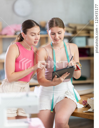 Two fashion designers drawing a sketch on a tablet 128435177
