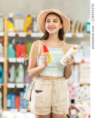 Woman choosing tanning products and sunscreen in the supermarket Woman choosing tanning products and sunscreen in the supermarket 128435259