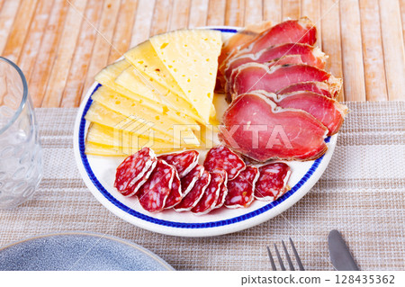 Circles of sausage butifarra, slices of prosciutto ham are complemented by triangular sliced cheese 128435362