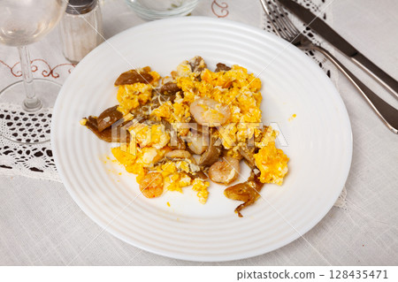Hearty and healthy meal is fried scrambled eggs with pieces of mushrooms, herbs and shrimp 128435471