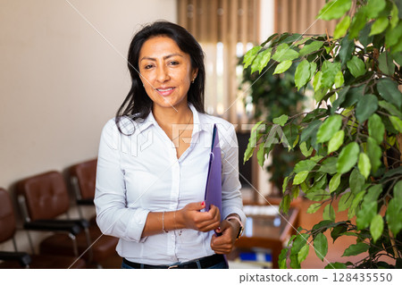 Positive secretary with folder for documents in office 128435550