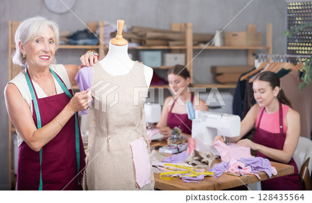 Woman and girl tailors sewing, senior female designer work with mannequin. 128435564