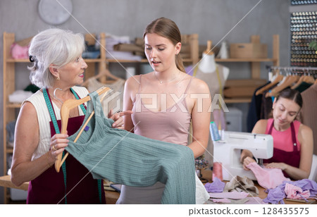 Mature female dressmaker showing a dress sample 128435575