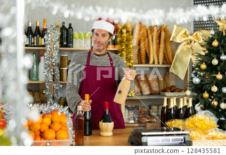 Vendor in apron and Santa hat offering alcoholic drinks for Christmas celebration 128435581