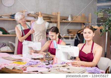 Woman and girl tailors sewing, senior female designer work with mannequin. 128435627