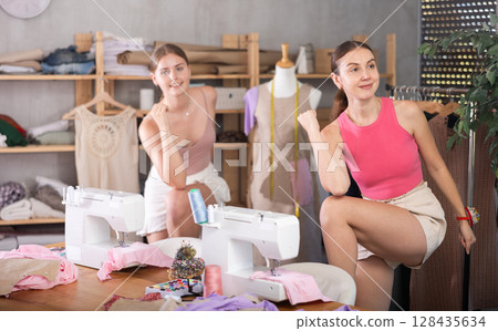 Young and adult women doing warm-up exercises in sewing workshop 128435634