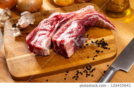 Fresh raw pork ribs with potatoes, onions and black pepper on wooden table Fresh raw pork ribs with potatoes, onions and black pepper on wooden table 128435641