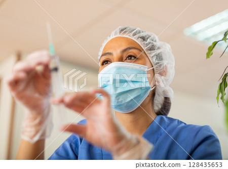 Confident young female doctor holding syringe for injection 128435653