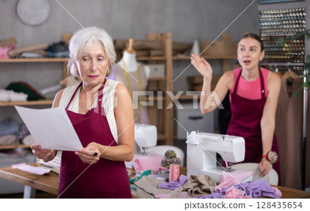 Adult female tailor scolding assistant with document for dismissal 128435654