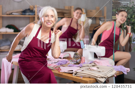 team of dressmakers doing a warm-up in the workshop team of dressmakers doing a warm-up in the workshop 128435731
