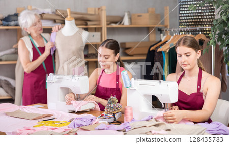 Woman and girl tailors sewing, senior female designer work with mannequin. 128435783