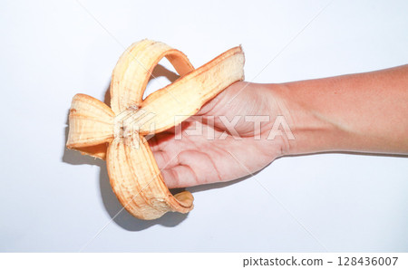 Woman holding peeled banana in hand on a white background. banana peel as compost material, organic waste, 128436007