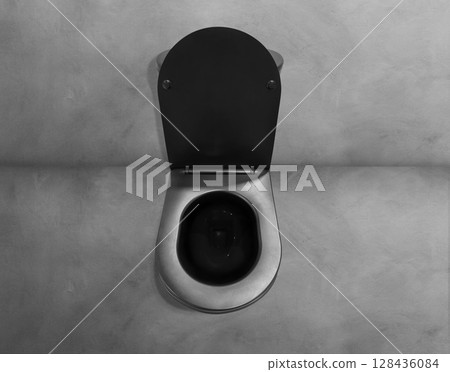 Top view of black toilet bowl with open lid on cement floor. 128436084