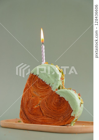Festive holiday candle birthday anniversary celebration Heart shaped pistachio croissant on green background with copy space. Puff pastry trendy sweet dessert bakery. Creamy dough experiment  128436606