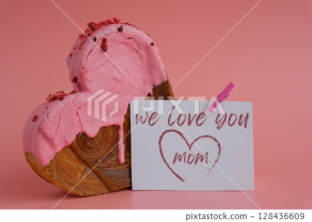 WE LOVE YOU MOM message on paper note greeting card Mother's Day Delicious fresh croissant topped with colorful flavor Ganache. Creation unique heart shape bakery. Puff pastry holiday love gift WE LOVE YOU MOM message on paper note greeting card Mother's Day Delicious fresh croissant topped with colorful flavor Ganache. Creation unique heart shape bakery. Puff pastry holiday love gift 128436609
