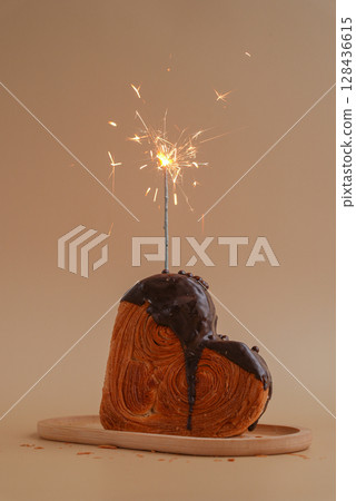 Birthday celebration cake candy sparkler Delicious fresh croissant topped with Dark chocolate flavor Ganache. Creation unique heart shape bakery. Puff pastry holiday love gift present idea Valentine's 128436615