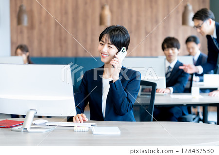 在辦公室使用智能手機的女商人 在辦公室使用智能手機的女商人 128437530