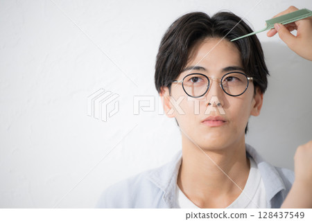 Close-up of a refreshing man wearing glasses Image of hair care and hair styling 128437549