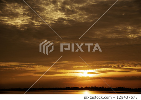 Tropical amazing dramatic golden sky on sunset over scenic river lake seascape ocean. Silhouette tranquil season wilderness serene landscape. Tranquil lake countryside sunrise seaside reflection 128437675